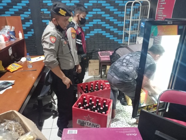 PENINDAKAN: Polisi mengangkut botol miras yang diedarkan secara ilegal di tempat karaoke tak berizin di Jalan Bypass menuju Mapolres Mojokerto Kota, Rabu (29/6) malam.