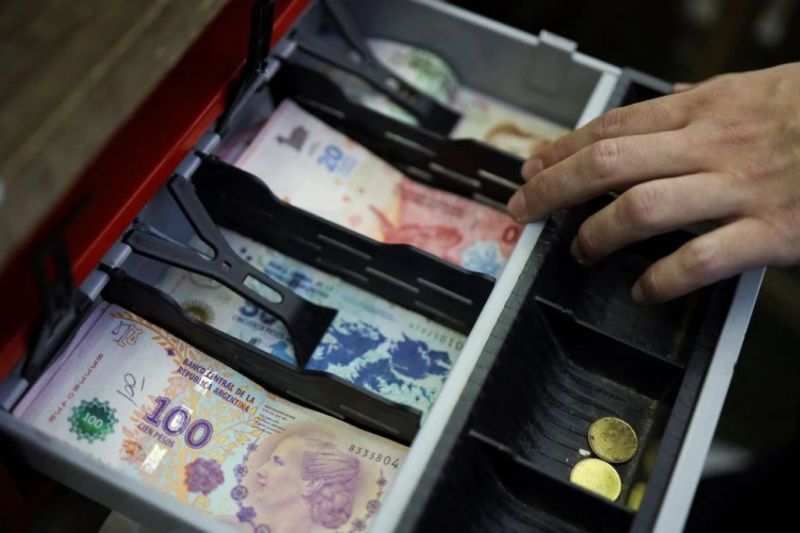 Seorang kasir menatap kotak penyimpan uang di Bouenos Aires, Argentina pada 23 Mei 2022. Mata uang peso Argentina terus terdevaluasi karena inflasi. (REUTERS)