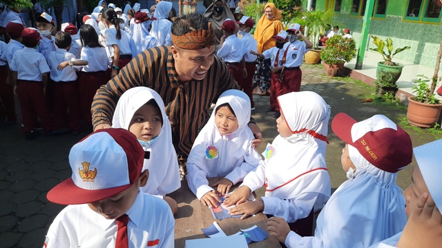 KREATIF: Kepala SDN Wates 5 N. Chania Zamzani mendampingi siswa baru memainkan game puzzle untuk pengenalan tenaga pendidik di hari pertama MPLS, Senin (18/7).