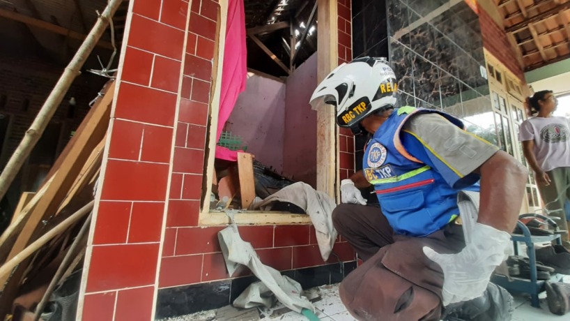 PORAK PORANDA: Seorang relawan mengamati kerusakan rumah korban akibat ledakan yang diduga dari petasan. (Rizal Amrulloh/Jawaposradarmojokerto.id)