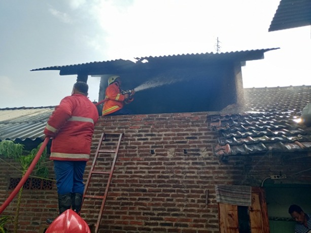 PENANGANAN: Petugas Damkar Kota Mojokerto menyemprotkan api ke bagian bangunan yang terbakar di Lingkungan Kedungsari, Kelurahan Gunung Gedangan, Kecamatan Magersari, Kota Mojokerto, kemarin.