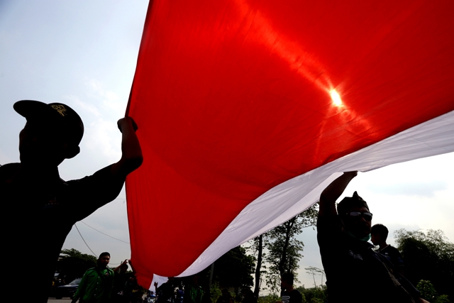 MERIAH: Bendera merah putih ukuran raksasa diarak di sepanjang jalan penghubung Desa Ngabar dan Desa/Kecamatan Jetis dalam kegiatan ritual tutup suro, kemarin. (Sofan Kurniawan/Jawa Pos Radar Mojokerto)