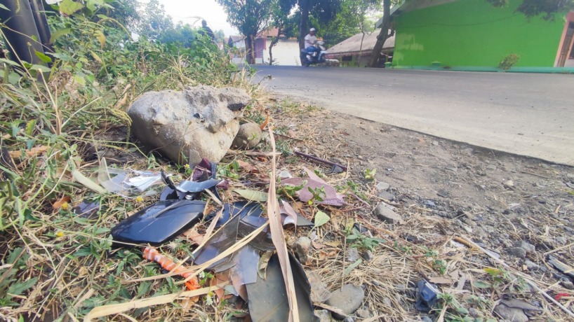 NAHAS: Warga tengah menunjukkan serpihan helm dan bagian motor korban yang ringsek parah akibat menyeruduk bak truk yang tengah parkir.