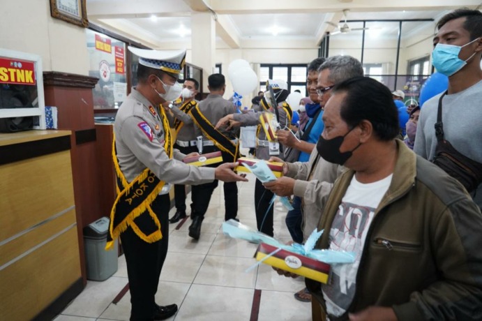MERIAH: Kasatlantas Polres Mojokerto Kota AKP Heru Sudjio Budi Santoso memberikan bingkisan kepada wajib pajak di KB Samsat Mojokerto, Senin (19/9).