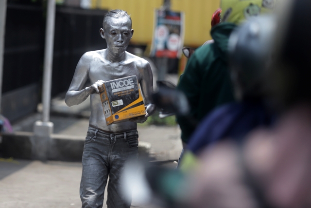 KEBERADAAN manusia silver meminta-minta sumbangan dari pengendara di Simpang Kenanten, Kecamatan Puri Kabupaten Mojokerto, kemarin (14/10). (Sofan Kurniawan/Jawa Pos Radar Mojokerto)