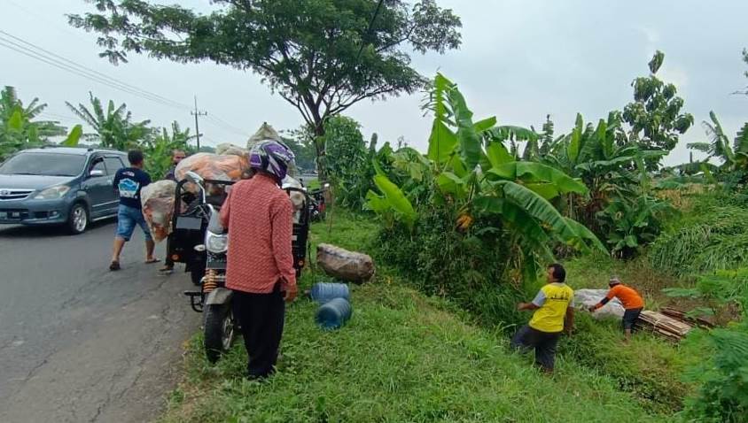 DIEVAKUASI: Sejumlah warga dan relawan tengah mengevakuasi motor dorkas muatan rosokan yang terperosok dan terguling di sekitar Jalan Raya Trawas - Mojosari, Desa Purworejo, Kecamatan Pungging, Senin (28/11) siang.