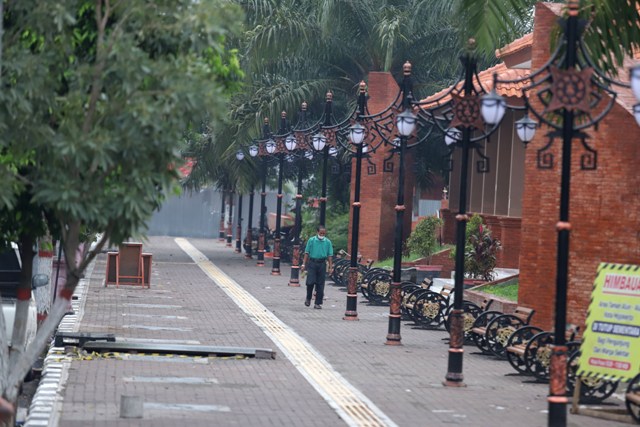WAJAH BARU: Warga berjalan di jalur pedestrian sisi timur Alun-Alun Kota Mojokerto dengan perwajahan baru dengan keberadaan lampu hias dan kursi taman dengan ornamen gaya ukiran Majapahit, kemarin (18/11). (Sofan Kurniawan/Jawa Pos Radar Mojokerto)