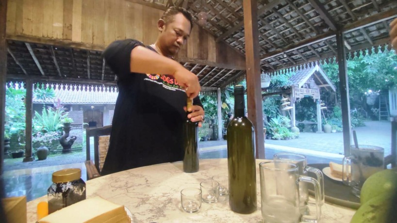 UNIK: Teguh tengah menuangkan minuman tradisional buah maja yang diolah secara winery  yang terasa layaknya wine anggur. (Martda Vadetya/Jawa Pos Radar Mojokerto)