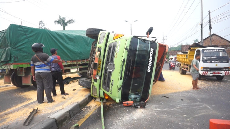 KECELAKAAN TUNGGAL: Truk bermuatan jagung terguling setelah menolak diarahkan petugas masuk jembatan timbang di Jalan Raya Trowulan, Jumat (2/11). (Mu