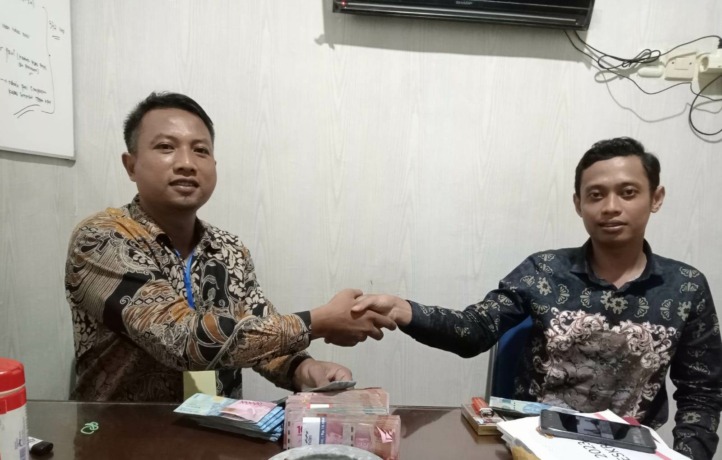 DAMAI: Khusnul Fasikin menerima uang pengembalian dari suami terlapor dengan disaksikan penyidik Satreskrim Polres Mojokerto Kota.
