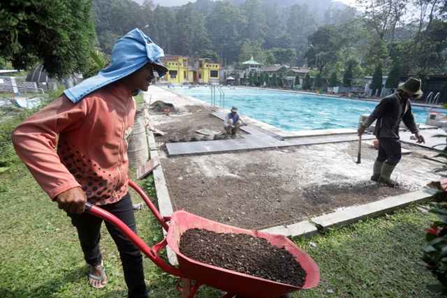 DIPERBAIKI: Sejumlah pekerja melakukan perbaikan lantai bibir kolam renang di kawasan wisata air panas Padusan, Kecamatan Pacet. Jelang libur Nataru destinasi wisata unggulan milik Pemkab Mojokerto ini terus dipoles.