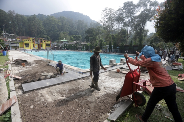 pekerja melakukan perbaikan lantai bibir kolam renang di kawasan wisata air panas Padusan, Kecamatan Pacet, Kabupaten Mojokerto, Jumat (9/12) kemarin. (Sofan Kurniawan/Jawa Pos Radar Mojokerto)