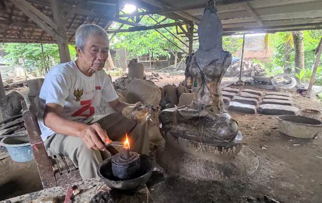 MELEGENDA: Hariadi Sabar, 65, tengah menata karyanya di workshop pribadinya di Dusun Kedungwulan, Desa Bejijong. Ia generasi pertama pelopor cor kuningan yang masih menekuni seni rupa warisan budaya Majapahit tersebut. (Martda Vadetya/Jawa Pos Radar Mojok