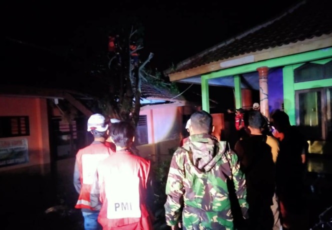 DIEVAKUASI: Tim gabungan BPBD Kabupaten Mojokerto tengah mengevakuasi pohon tumbang yang menimpa salah satu kelas SMPN 3 Pacet, kemarin. (Martda Vadetya/JPRM)
