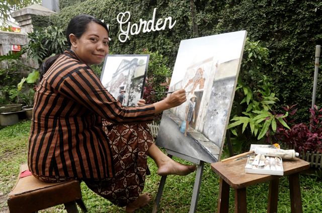 HISTORIS: Nathallia tengah asyik melukis foto hasil bidikannya terkait salah satu tempat bersejarah di salah satu kawasan Kota Mojokerto. (Sofan Kurniawan/JPRM)