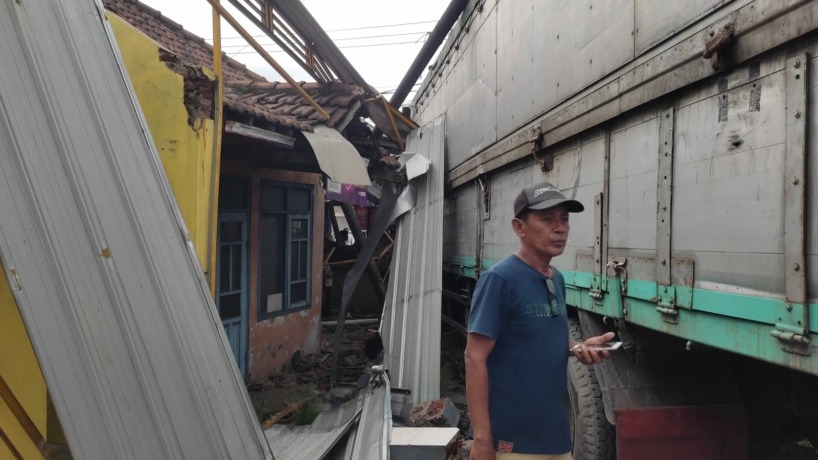 RINGSEK: Kabin truk tronton bernopol L 9194 AN  ringsek akibat menghantam pagar penitipan motor di Simpang Empat Trowulan, kemarin sore. (Martda Vadetya/JPRM)
