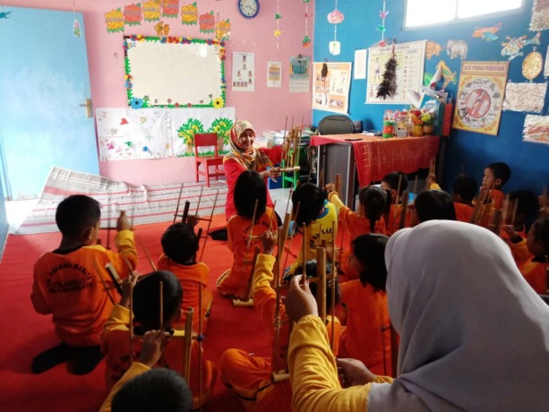 KREATIF: Kepala TK Dharma Wanita Pulorejo Endah Rakhmawati mengajarkan anak didik TK Dharma Wanita Pulorejo memainkan angklung.  (Rizal Amrulloh/JPRM)