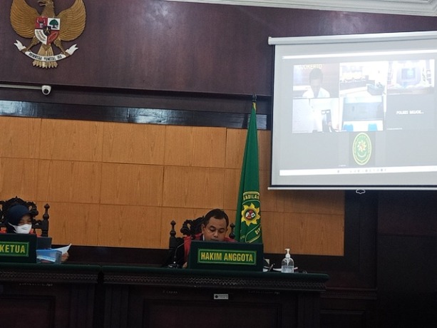 MENUNDUK: Terdakwa (baju putih di layar) mengikuti sidang vonis secara online di Ruang Cakra PN Mojokerto, kemarin. (Yulianto Adi Nugroho/JPRM)