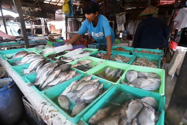 MEROKET: Suwarno, pedagang ikan di Pasar Tanjung Anyar Kota Mojokerto sedang menata dagangannya, kemarin. (Sofan Kurniawan/JPRM)