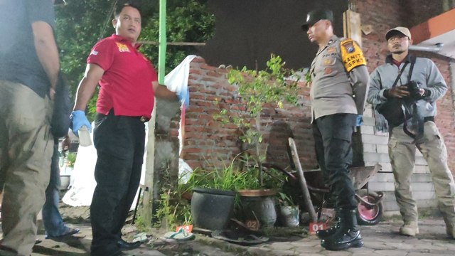 OLAH TKP: Petugas memasang garis polisi di tempat kejadian perkara penyerangan di kawasan Sinoman, Miji, Kecamatan Kranggan, Kota Mojokerto, Kamis (9/3) malam. (Farisma Romawan/JPRM)