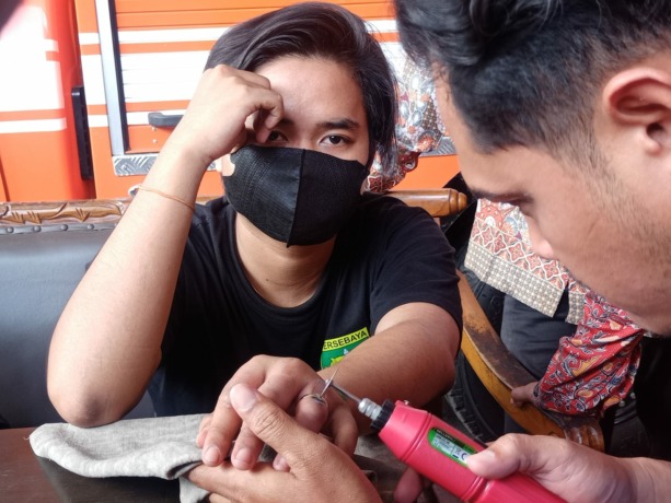 TERJEBAK: Petugas tampak tengah memotong cincin monel milik karyawan percetakan Desa Lebaksono, Kabupaten Mojokerto, Kamis (27/4).  (Yulianto Adi Nugroho/Jawa Pos Radar Mojokerto)