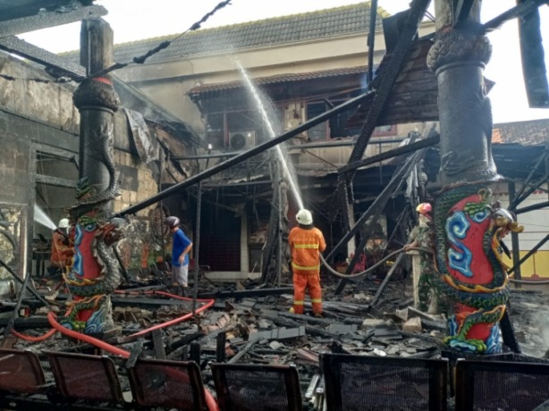 HANGUS: Kondisi kelenteng yang hangus terbakar tengah dilakukan pembasahan oleh petugas pemadam, Minggu (7/5). (Yulianto Adi Nugroho/JPRM)