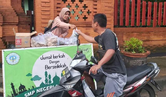 BERBAGI: Salah satu guru SMPN 3 Kota Mojokerto memberikan makanan dan minuman ke warga sekitar sekolah yang kurang mampu setiap Jumat. (Indah Oceananda/JPRM)