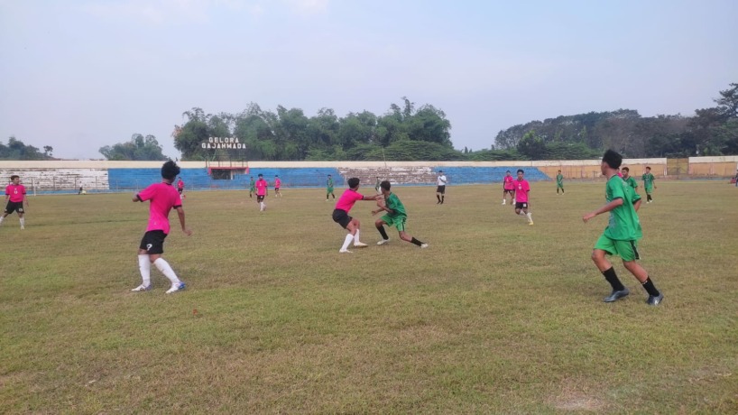 NGOTOT: Pemain Kabupaten Mojokerto (jersey hijau) berjibaku berebut bola dengan pemain Gresik saat uji coba di Stadion Gelora Gajah Mada Mojosari, Sabtu (27/5) sore. (Martda Vadetya/JPRM)