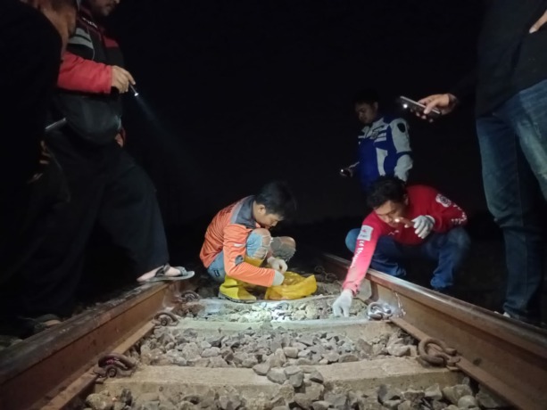 BERHAMBURAN: Petugas memungut serpihan tubuh korban yang disambar KA.(Adi Nugroho/JPRM)