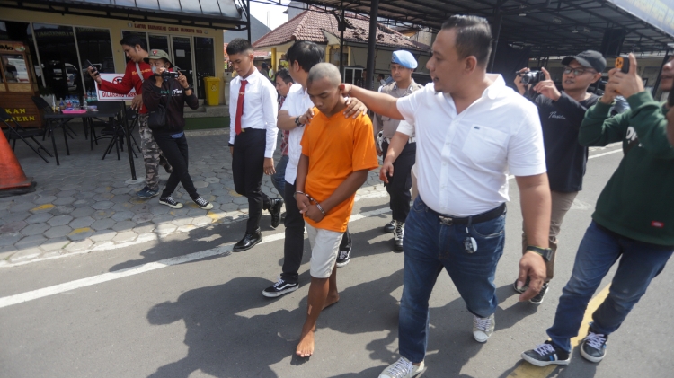PEMBUNUH KEJI: Mochammad Adi, 19, warga Dusun Randurejo, Desa Mojowatesrejo, Kabupaten Mojokerto pelaku dewasa pada kasus pembunuhan AE, siswi SMP Kemlagi dikeler petugas sebelum mengikuti pers rilis di Mapolres Mojokerto Kota, Rabu (14/6). (Sofan Kurniaw