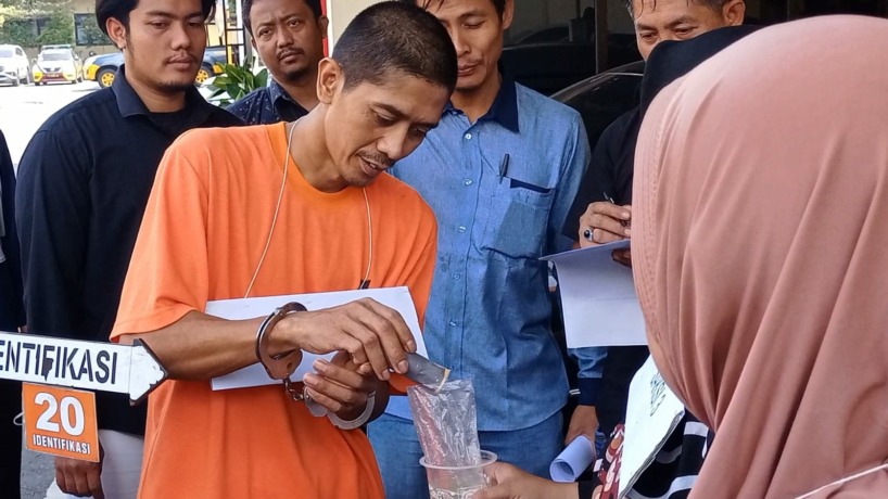 RACUN TIKUS: Tersangka Supaino Sanjaya memperagakan adegan menuangkan racun ke dalam minuman jus untuk korban saat rekontruksi pembunuhan di Mapolres Mojokerto, Kamis (8/6). (Adi Nugroho/JPRM)