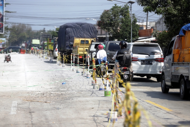 PADAT MERAYAP: Kendaraan angkutan berat dan penumpang melintasi jalur bypass yang hanya bisa dilintasi satu jalur saja imbas molornya pengerjaan pengecoran. (Sofan Kurniawan/JPRM)