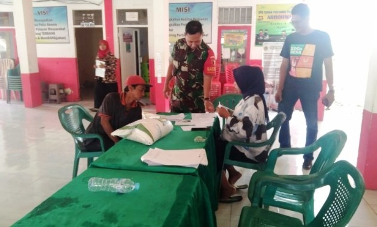 BANSOS: Babinsa Koramil Duduksampeyan Serda Suwarto membantu pembagian bansos beras kepada warga di Balai Desa Tirem, Kecamatan Duduksampeyan.