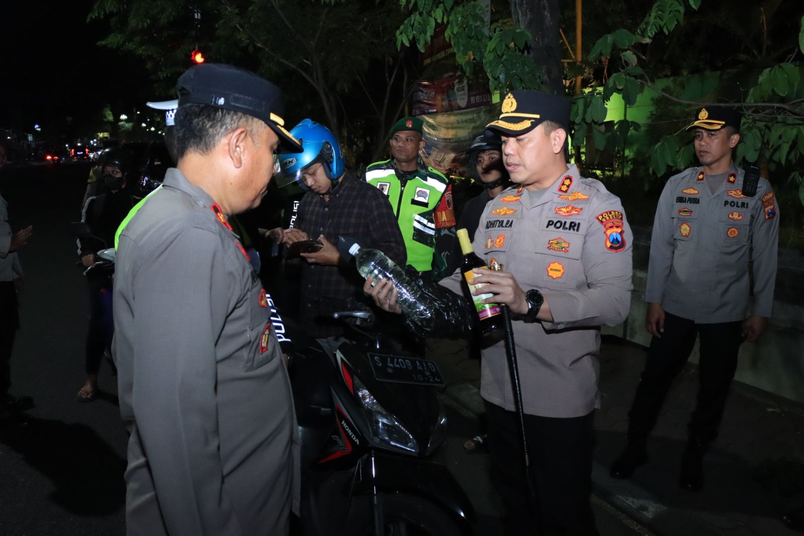 MIRAS: Kapolres Gresik Aditya Panji anom saat memeriksa dua botol yang diduga miras saat melakukan penyekatan di wilayah perbatasan Surabaya - Gresik.