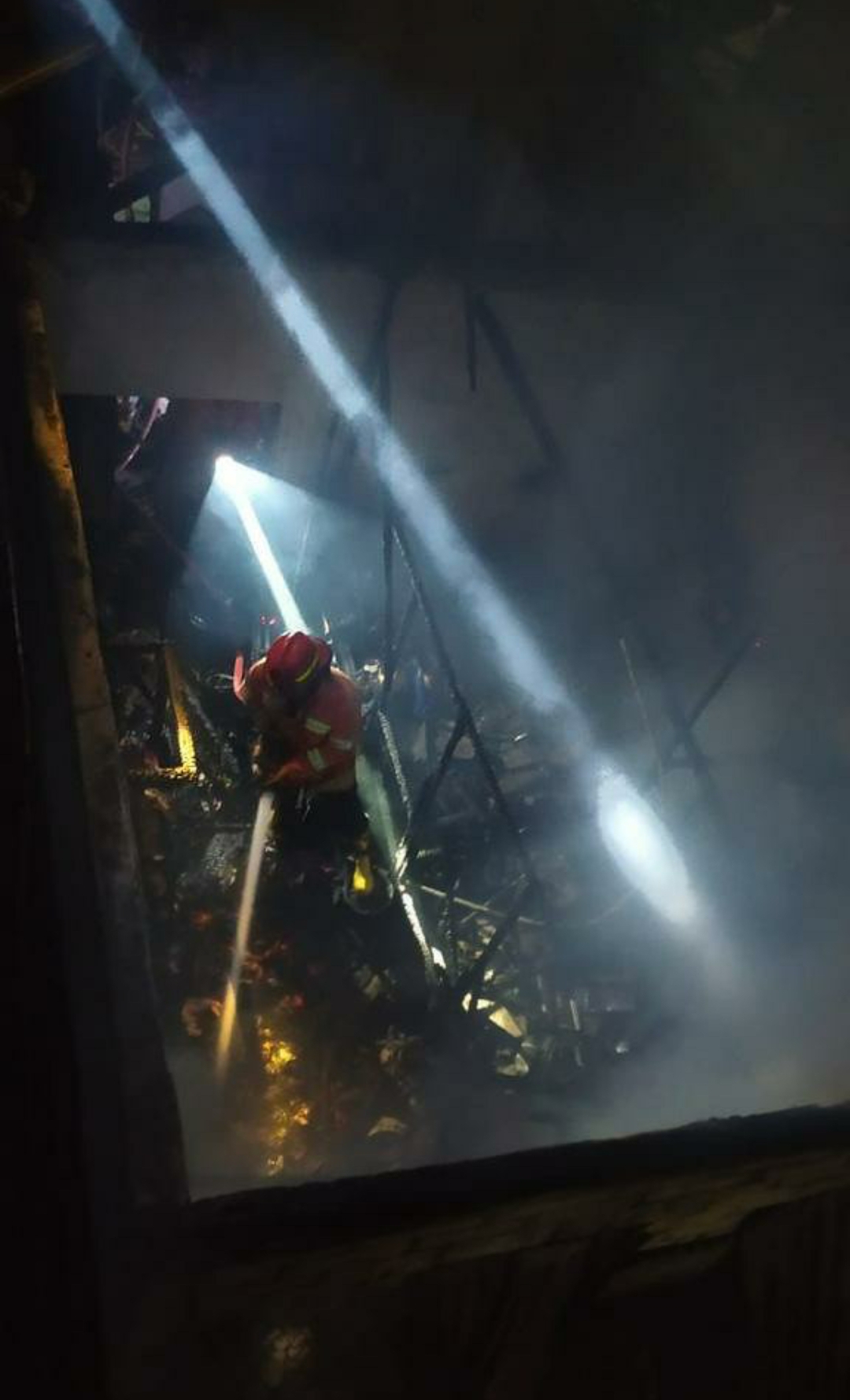 Jadi Arang : Petugas Damkarla menerobos masuk rumah milik Agus yang terbakar hebat untuk menyemprotkan air.