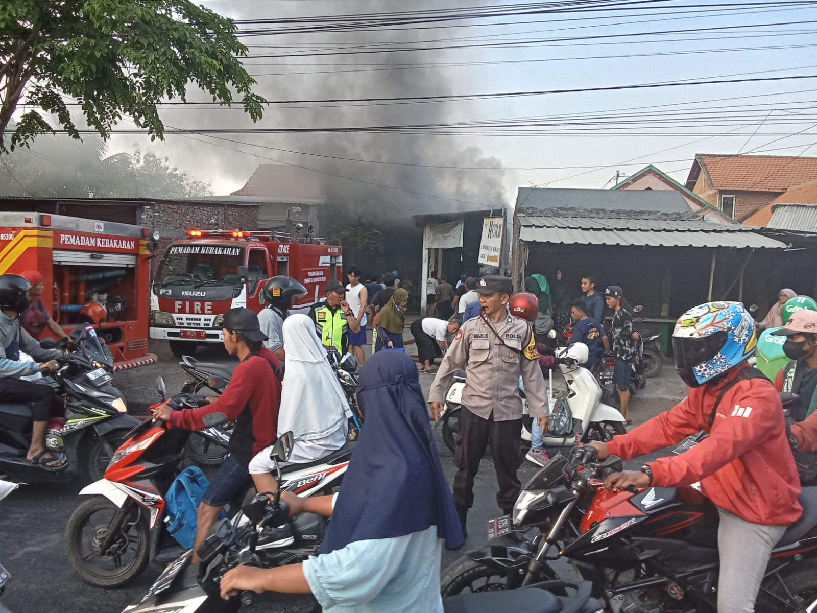 TERBAKAR: Anggota Damkarla melakukan pemadaman kebakaran di rumah toko sembako restu di jalan di jalan raya Desa Sidowungu, RT 01, RW 01, Kecamatan Menganti, Kamis (14/9).  (yudhi/radar gresik)