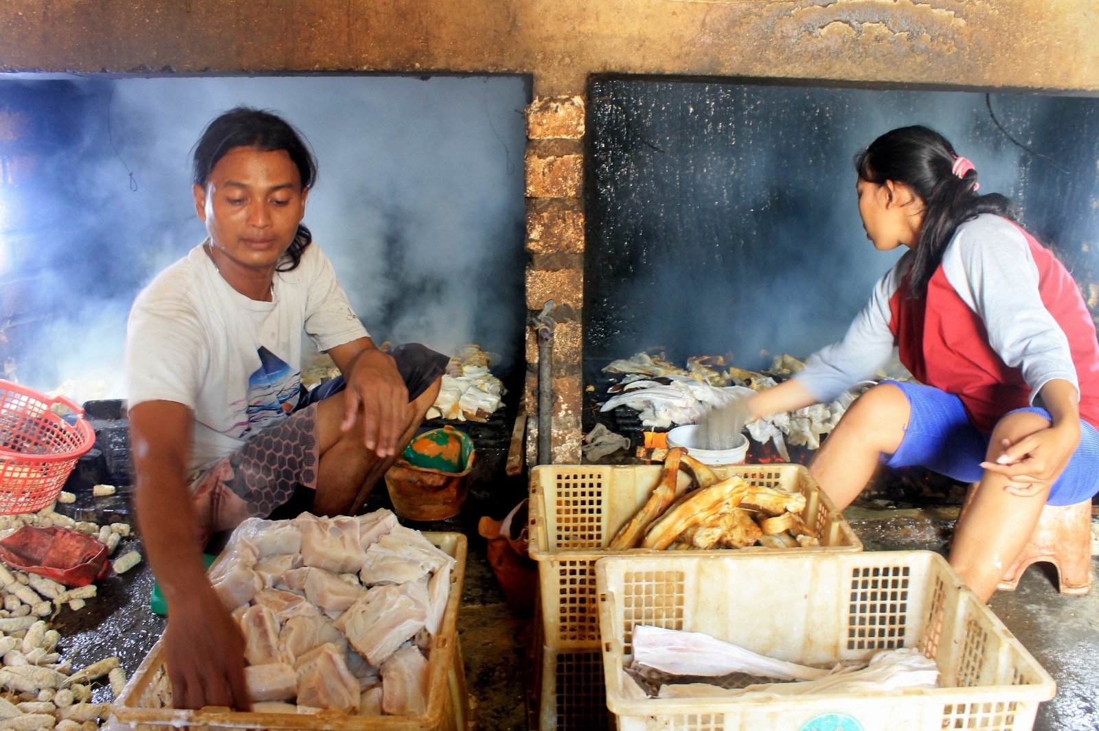 PENGASAPAN IKAN PARI: Asmaul Khoir melakukan pengasapan ikan pari di rumahnya di Desa Randuboto, Kecamatan Sidayu. (Foto : Yudhi/Radar Gresik)