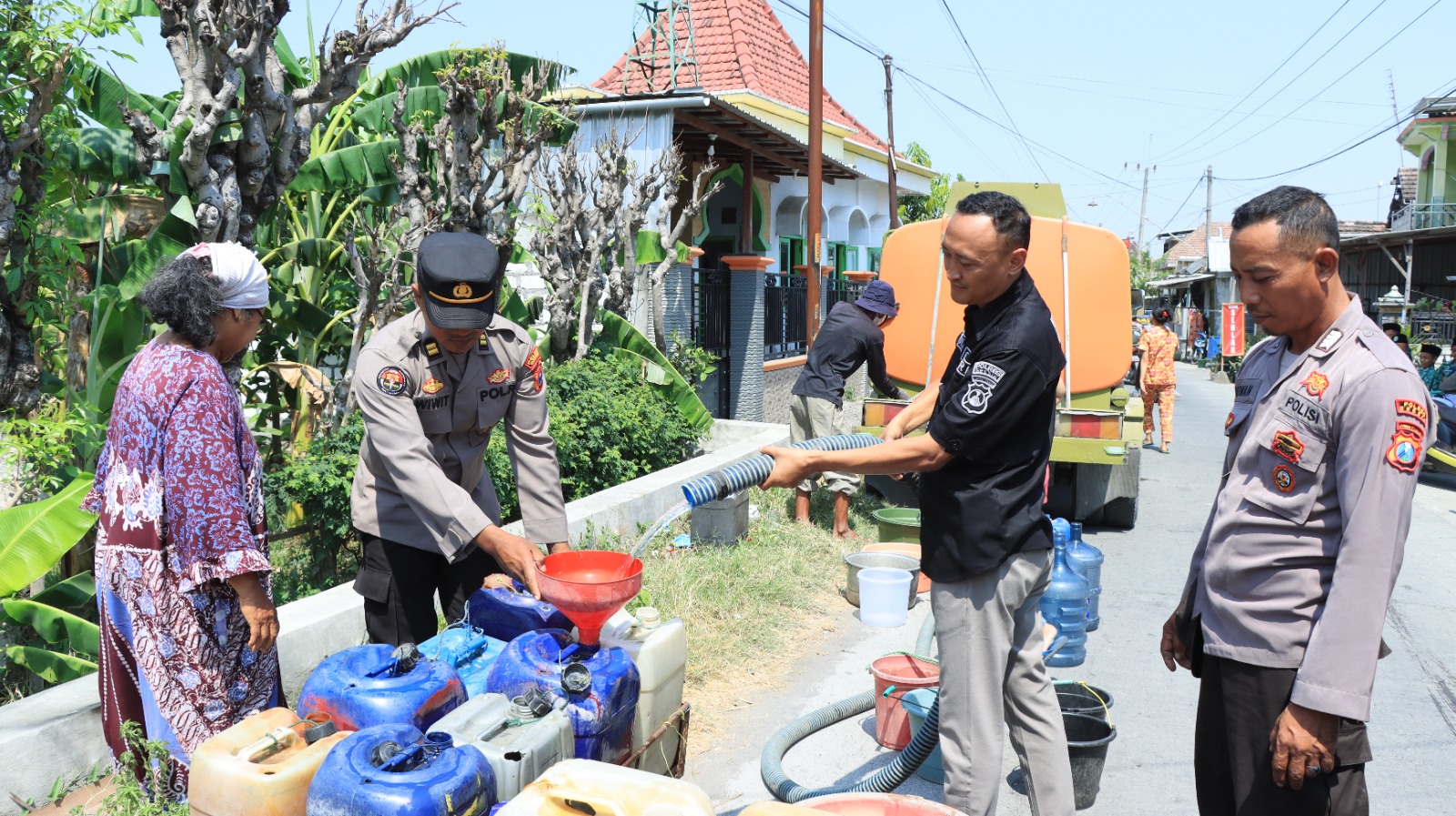 Foto : Istimewa/Radar Gresik  DROPING AIR: Anggota Humas Polres Gresik melakukan drooping air untuk warga yang membutuhkan air di musim kemarau di Kecamatan Duduksampeyan.