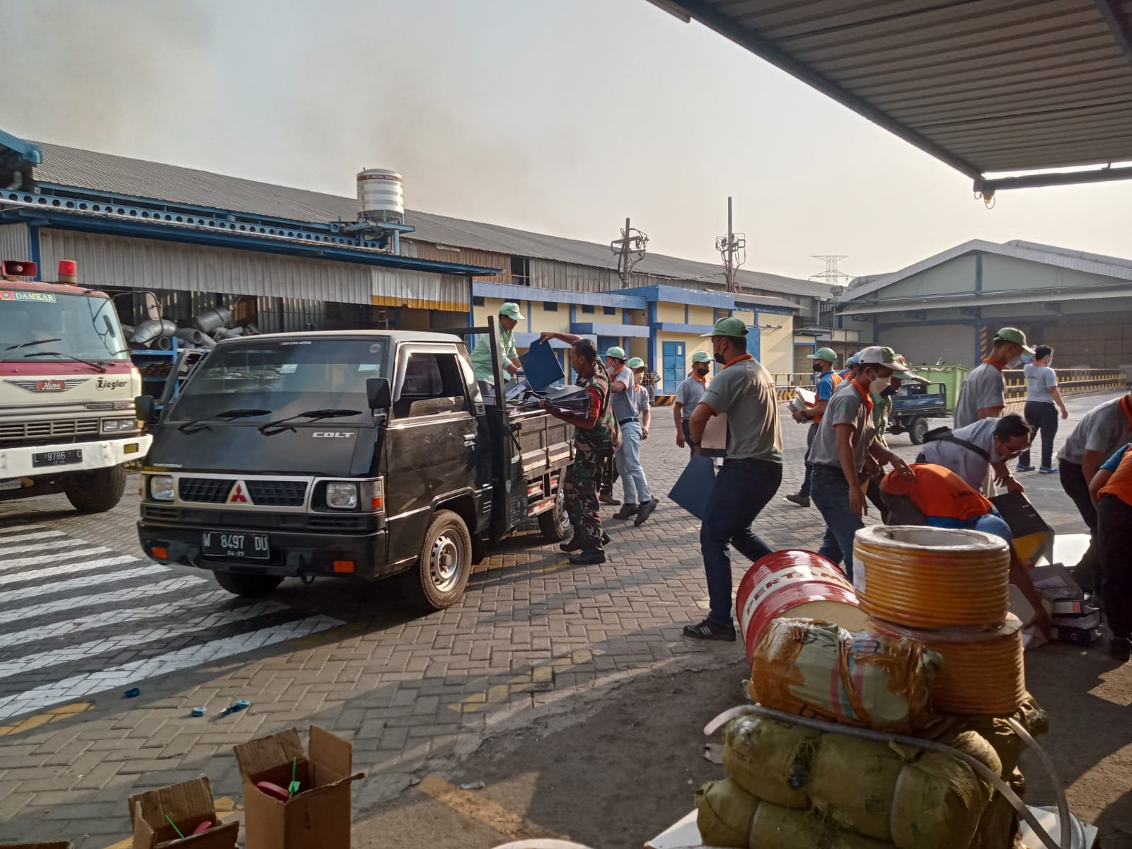 Foto : Istimewa/Radar Gresik  MENYELAMATKAN BERKAS: Para Karyawan PT Nankai Indonesia terlihat mengangkat berkas - berkas dari dalam pabrik yang terbakar, Kamis (12/10).