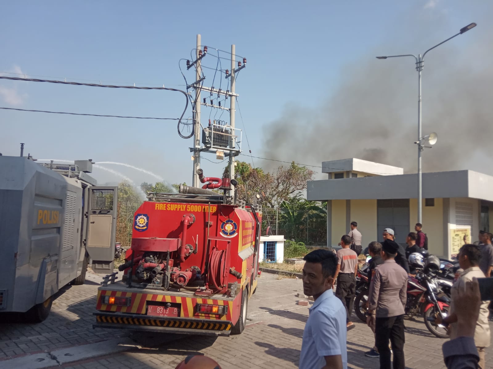 PEMADAMAN: Dua mobil dari Water Canon milik Polres Gresik dan satu mobil Damkarla Gresik melakukan pemadaman kebaran di lahan kosong samping Polres Gresik.