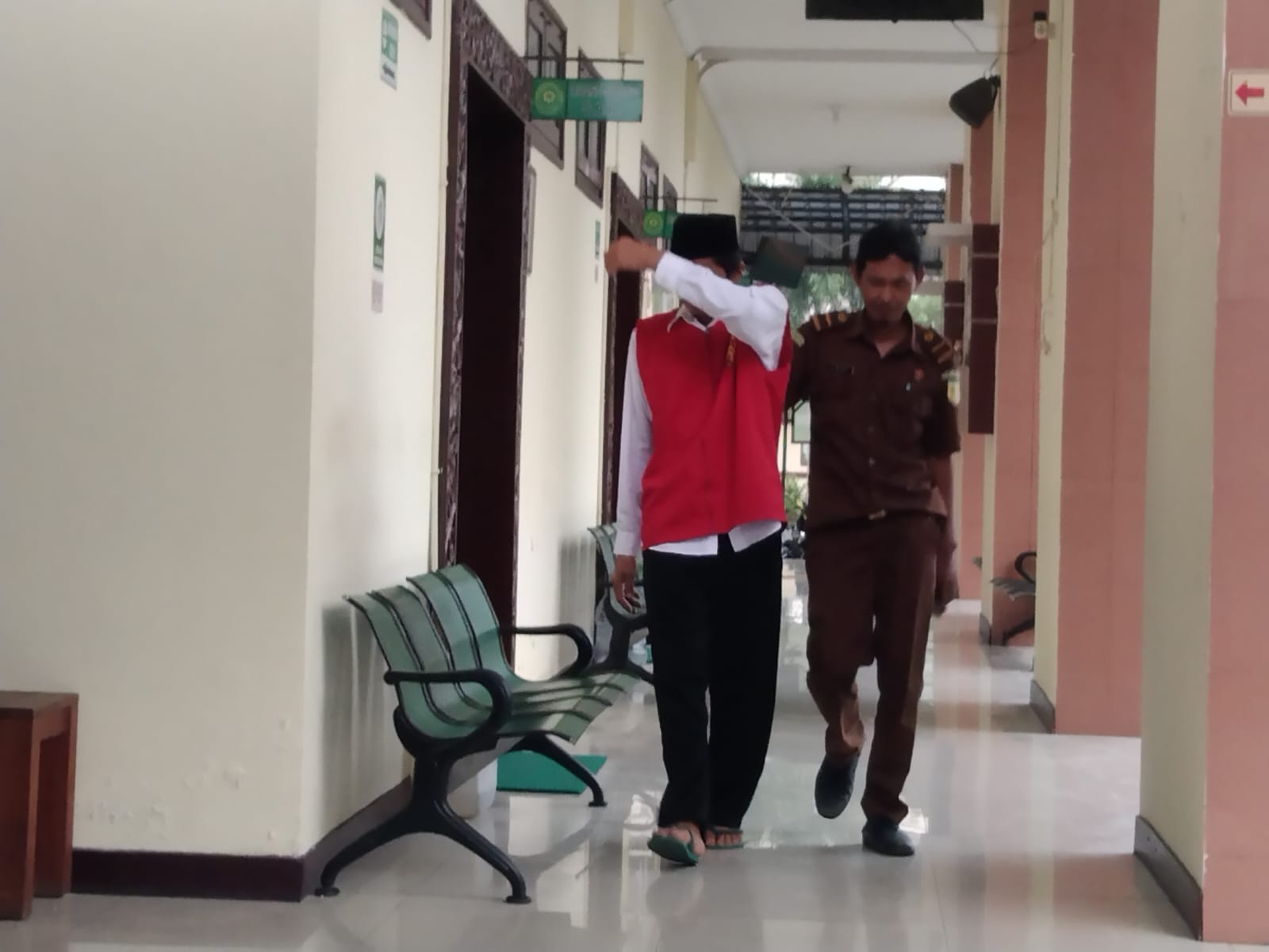 TUTUP MUKA: Terdakwa Ahmad Ashari menutupi wajahnya usai menjalani sidang tertutup di PN Gresik.