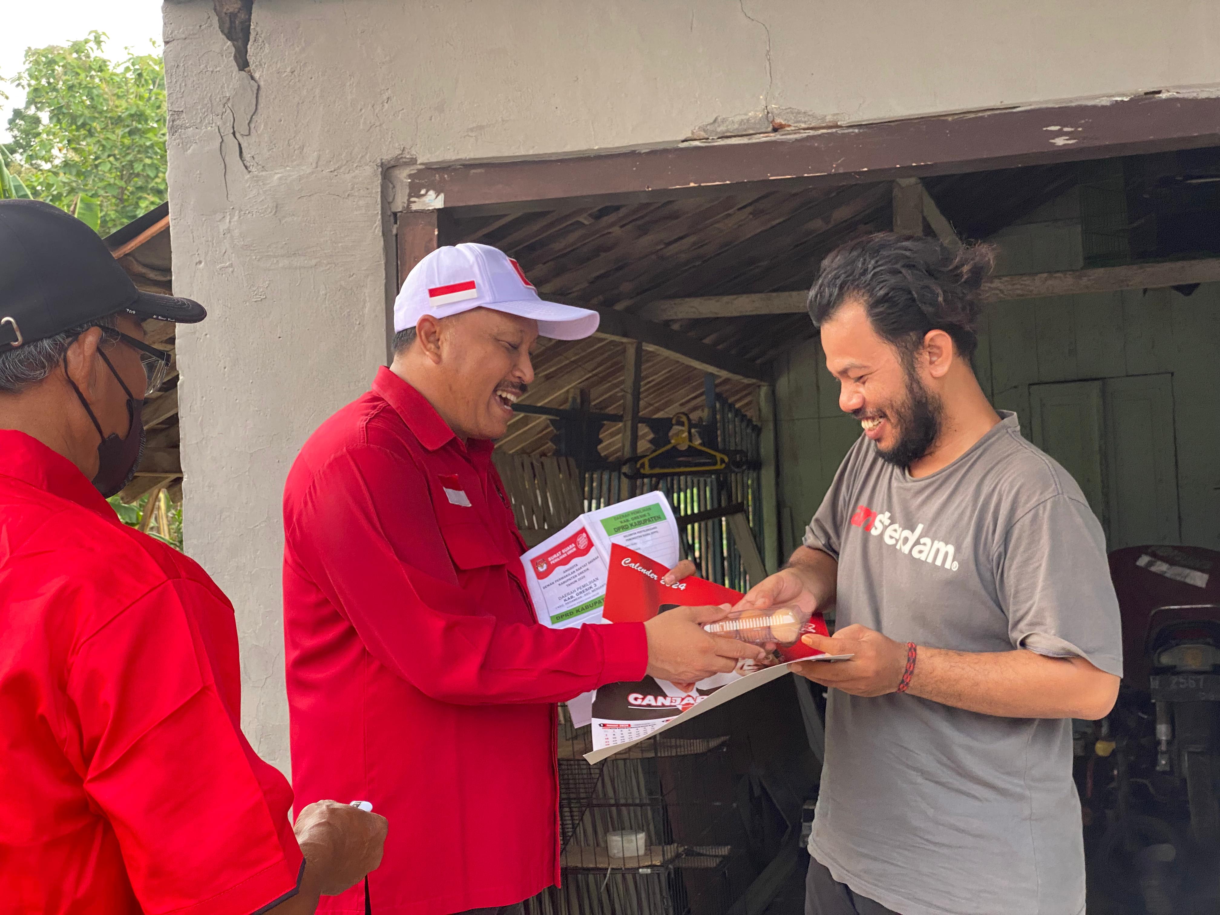 TURBA: Ketua DPC PDIP Gresik Mujid Riduan saat membagikan telur dan kalender Ganjar-Mahfud.