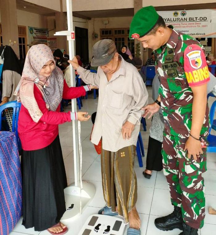 PENDAMPINGAN: Anggota Koramil Manyar Serda Vian melakukan pendampingan kegiatan posyandu lansia di Desa Gumeno, Kecamatan Manyar.