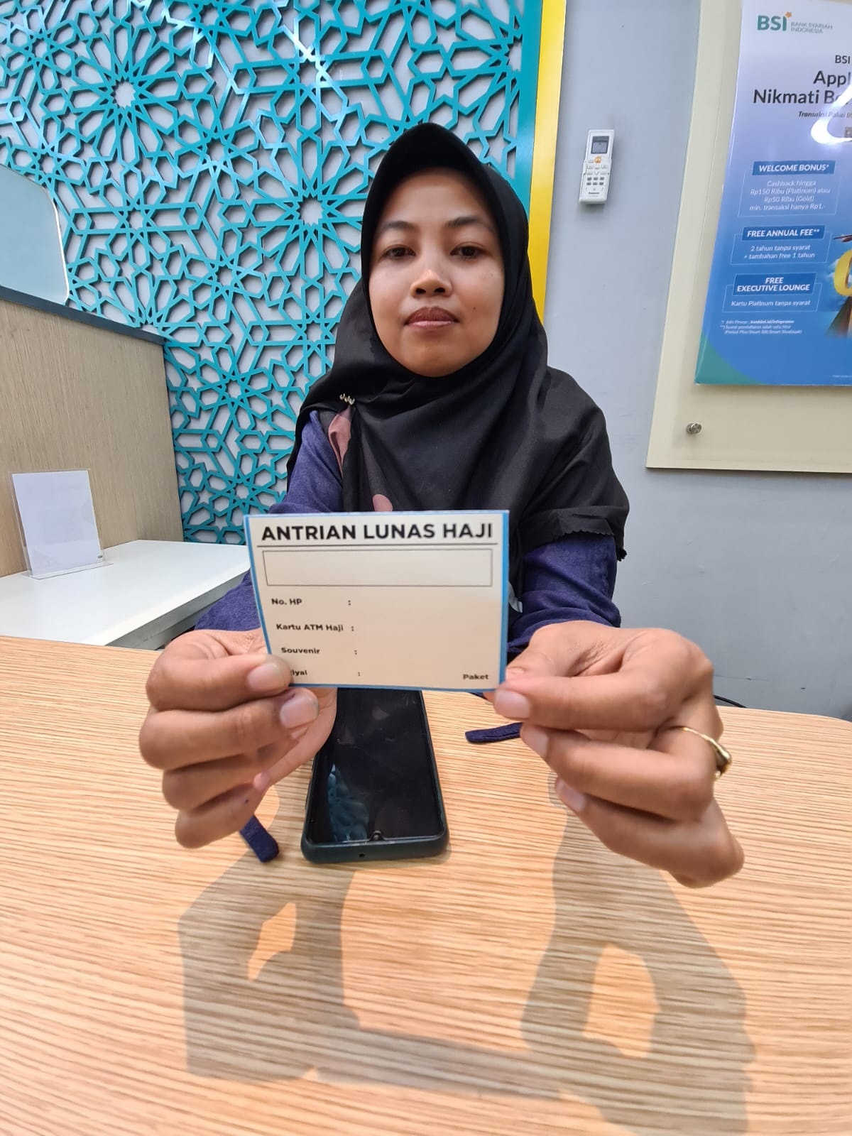 BIAR TERTIB: Supervisor Operasional BSI KC Gresik Kartini, Nur Faizah menunjukkan kartu antrean yang akan diberikan kepada CJH yang datang untuk melakukan pelunasan