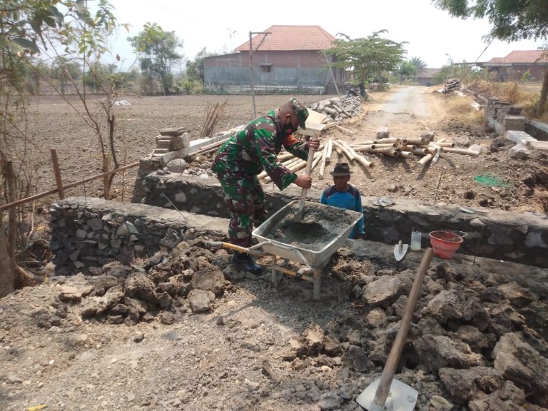 GOTONG ROYONG: Sertu Yudi Babinsa Koramil 0817/02 Wringinanom bersama warga bergotong royong membuat selokan air di jalan Desa Watestanjung, Kecamatan Wringinanom, Senin