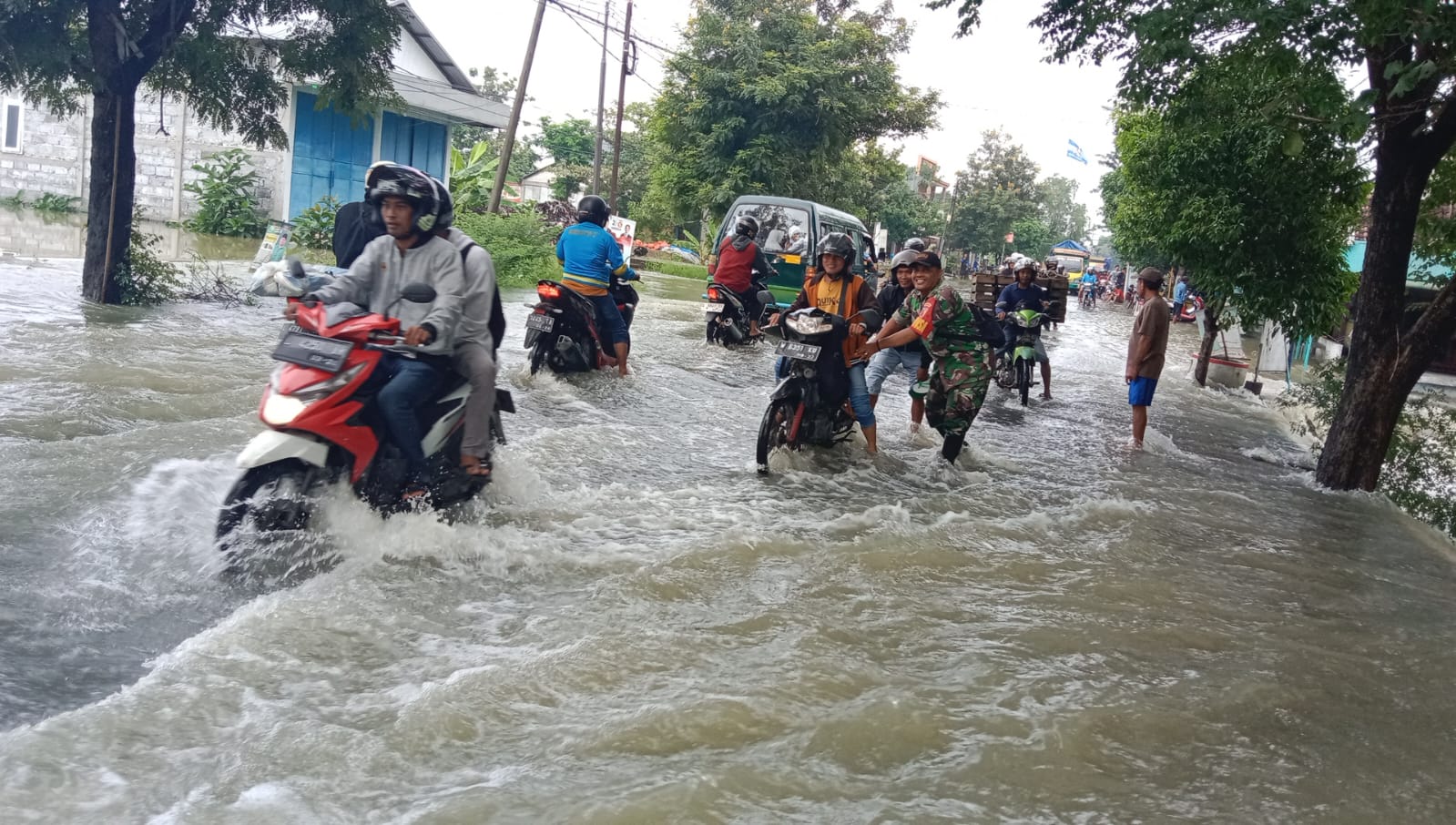 BANTU PENGENDARA : Anggota Koramil Benjeng saat membantu pengendara saat melintas di banjir luapan Kali Lamong Meluas, genangi lima Desa di Kecamatan Benjeng.
