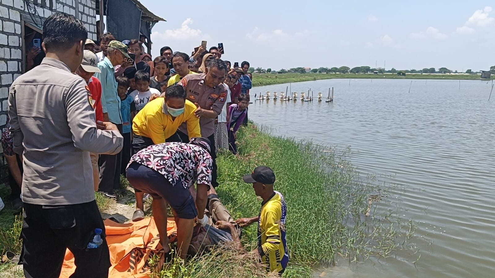 EVAKUASI : Anggota Polsek Manyar dibantu tim medis dan warga saat mengevakuasi korban di area tambak TKD milik Desa Sembayat RT 05 RW 02, Kecamatan Manyar.