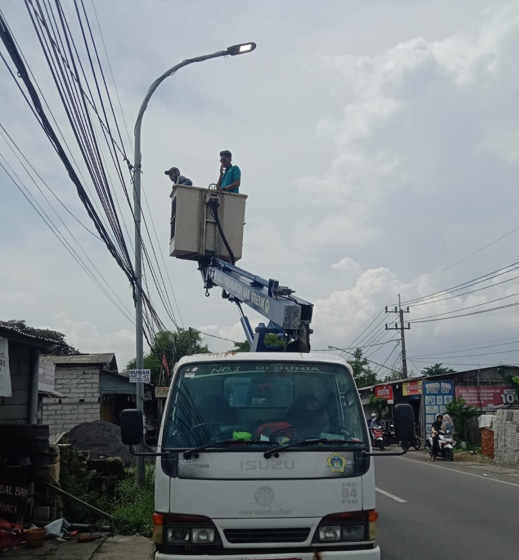 Tim Reaksi Cepat (TRC) Dishub Gresik saat melakukan perbaikan Penerangan Jalan Umum (PJU) di Jalan Petiken.