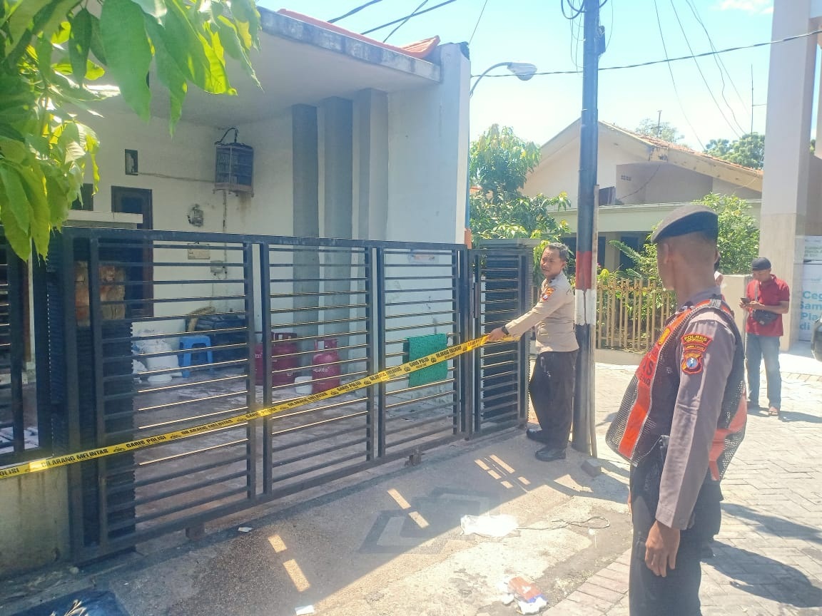 DIPOLICE LINE: Anggota Polsek Gresik Kota saat memasang police line di TKP kebakaran rumah home industri pembuat roti Papa Cookies Bakery di Perumahan BP Kulon, Ikan Gura