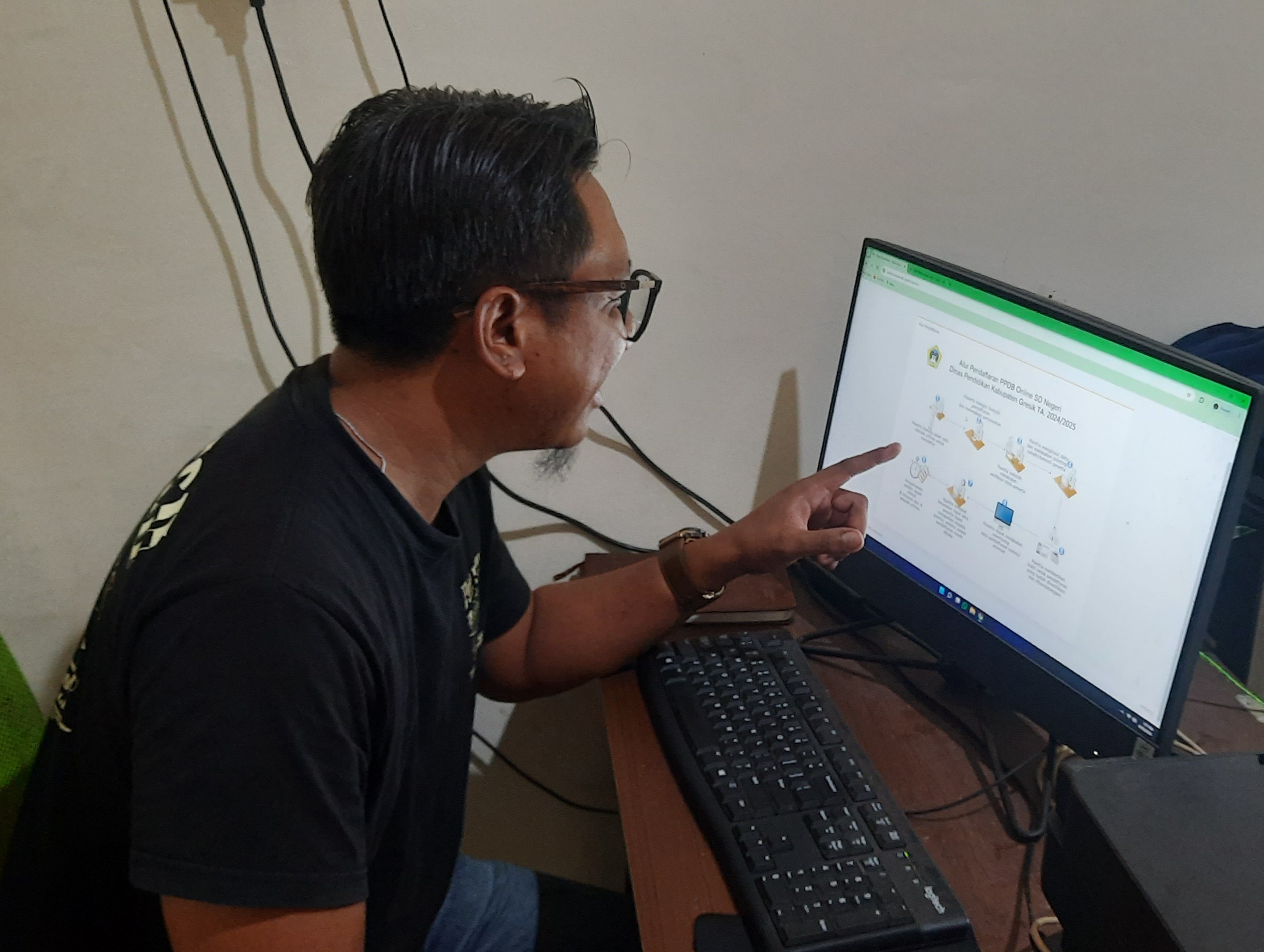 Salah satu wali murid saat mempelajari pendaftaran PPDB online jenjang SD Negeri melalui website yang disiapkan Dispendik Gresik.